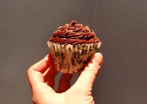 One chocolate cup cake being held up
